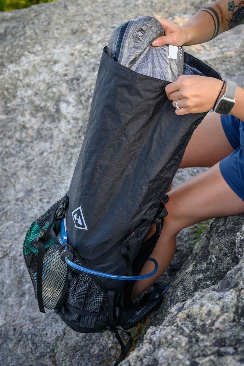 Osoba s rozbaleným batohem Batoh Hyperlite Mountain Gear 3400 Junction Black - kontrolující jeho obsah